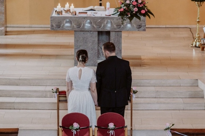 Ein Brautpaar steht in einer Kirche vor den Stufen des Altars.